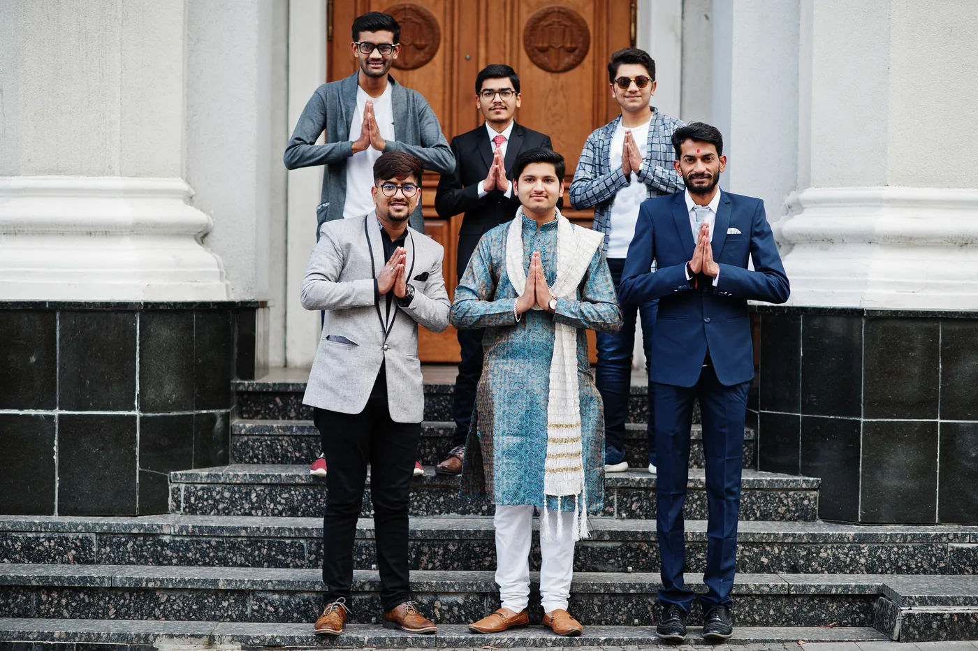 A group of South Asian men in formal and traditional attire